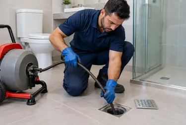 Técnico trabalhando no desentupimento de um ralo em Ubá.